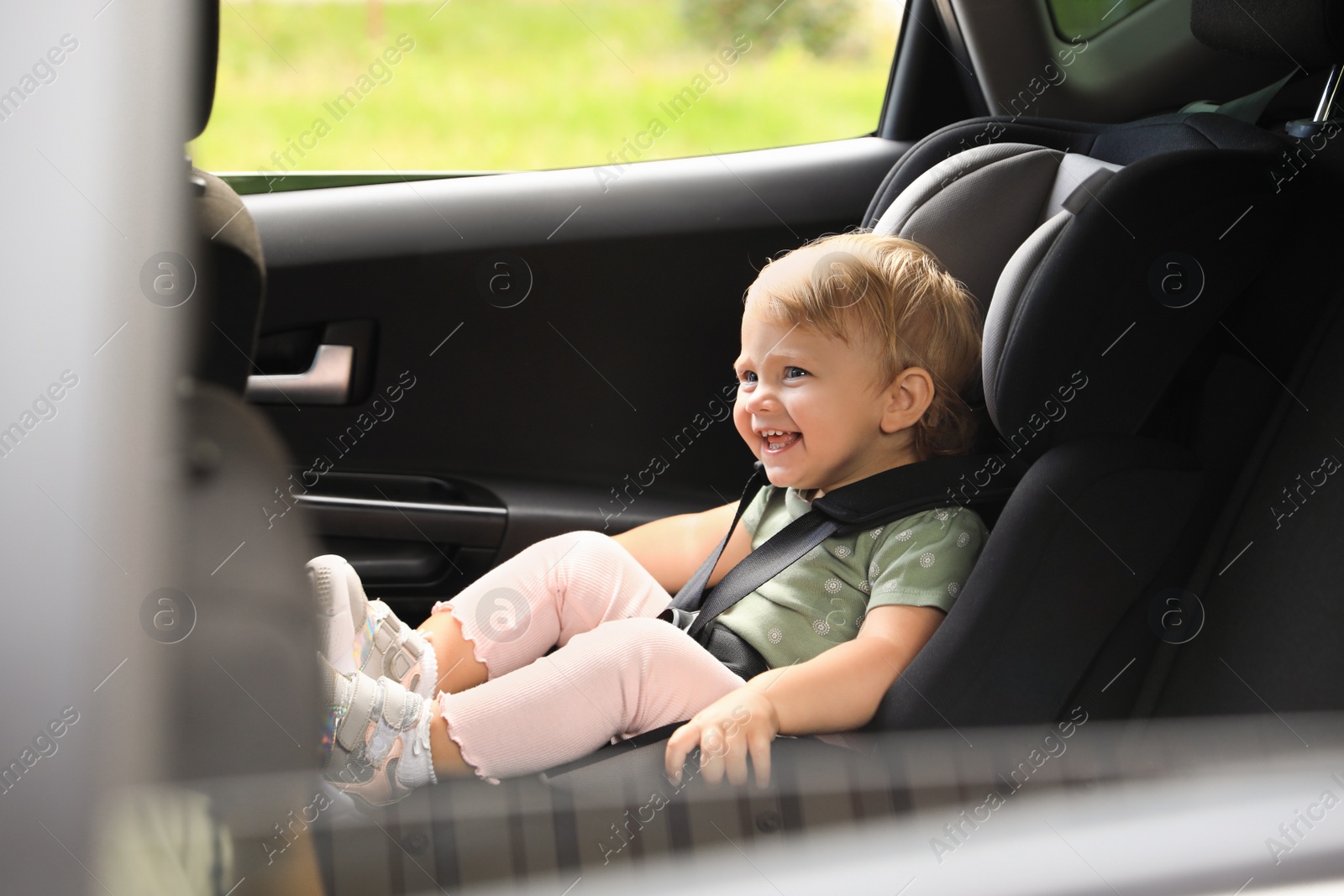 Photo of Cute little girl sitting in child safety seat inside car