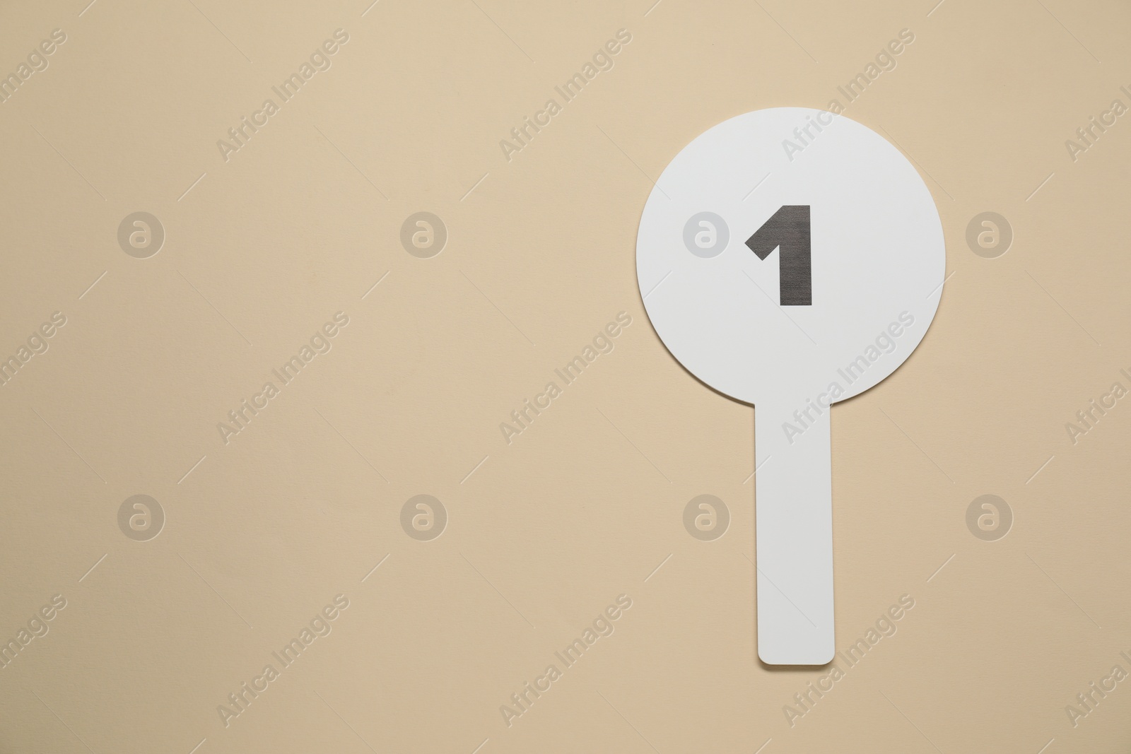 Photo of Auction paddle with number 1 on beige background, top view. Space for text