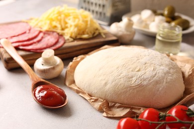 Photo of Pizza dough and products on gray textured table, closeup