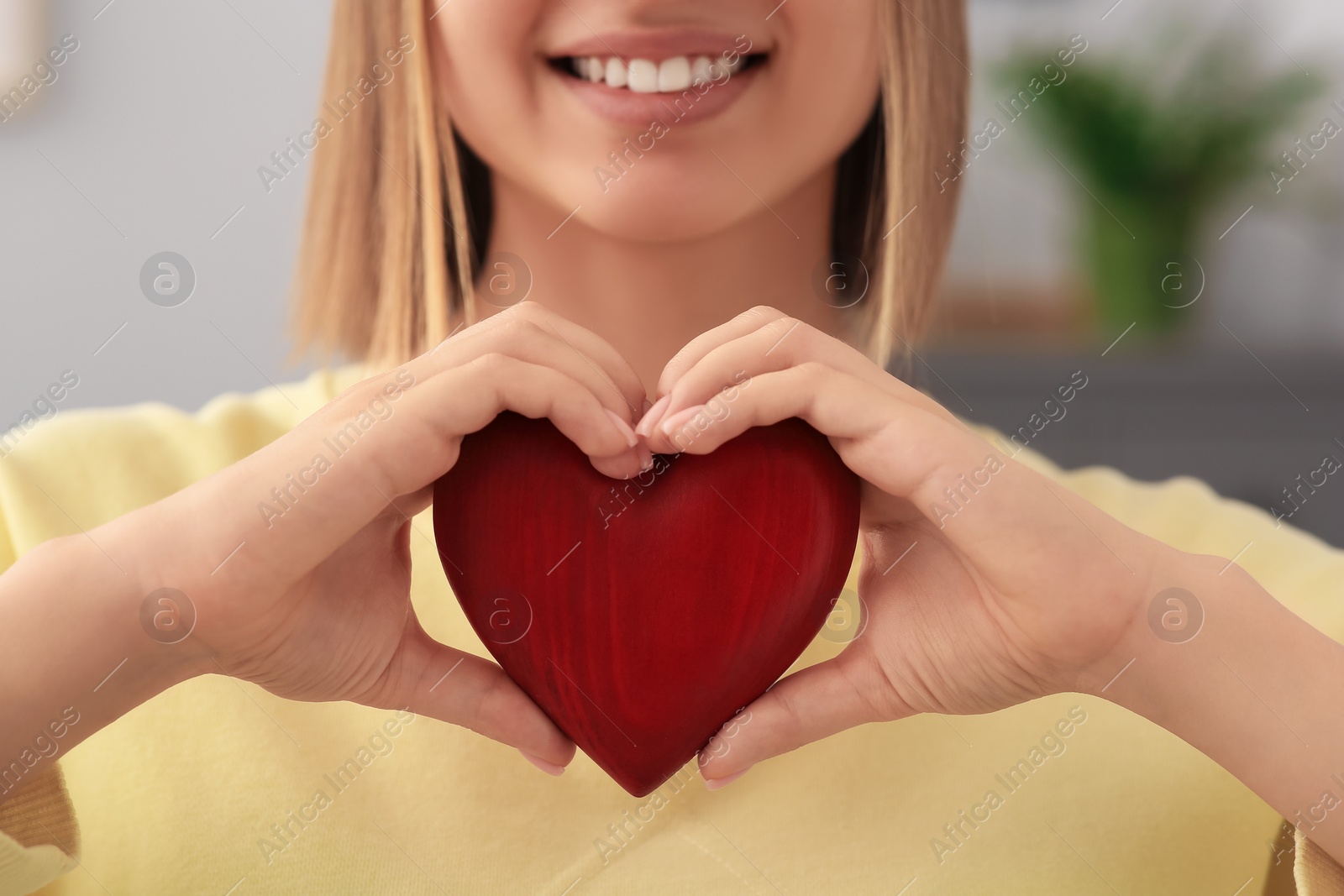 Photo of Young woman holding red heart indoors, closeup. Volunteer concept