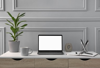 Photo of Stylish workspace with laptop, stationery and houseplant on wooden desk