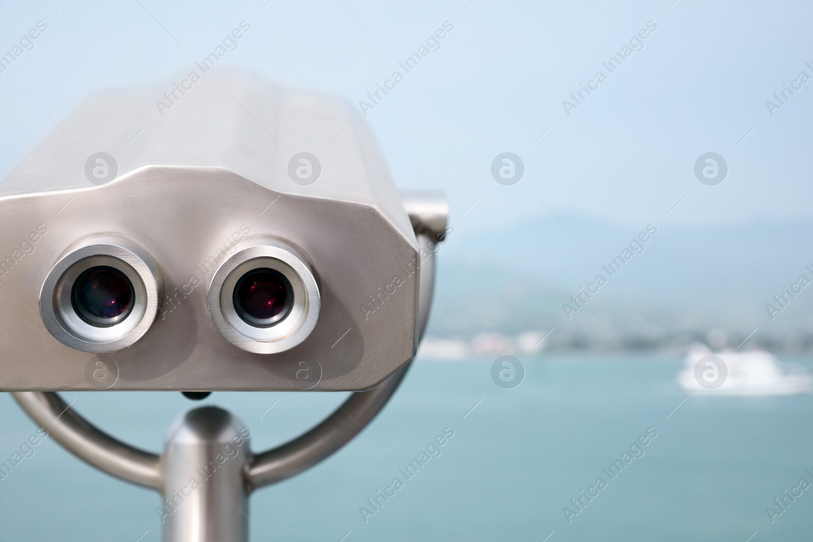 Photo of Metal tower viewer installed near sea, space for text. Mounted binoculars