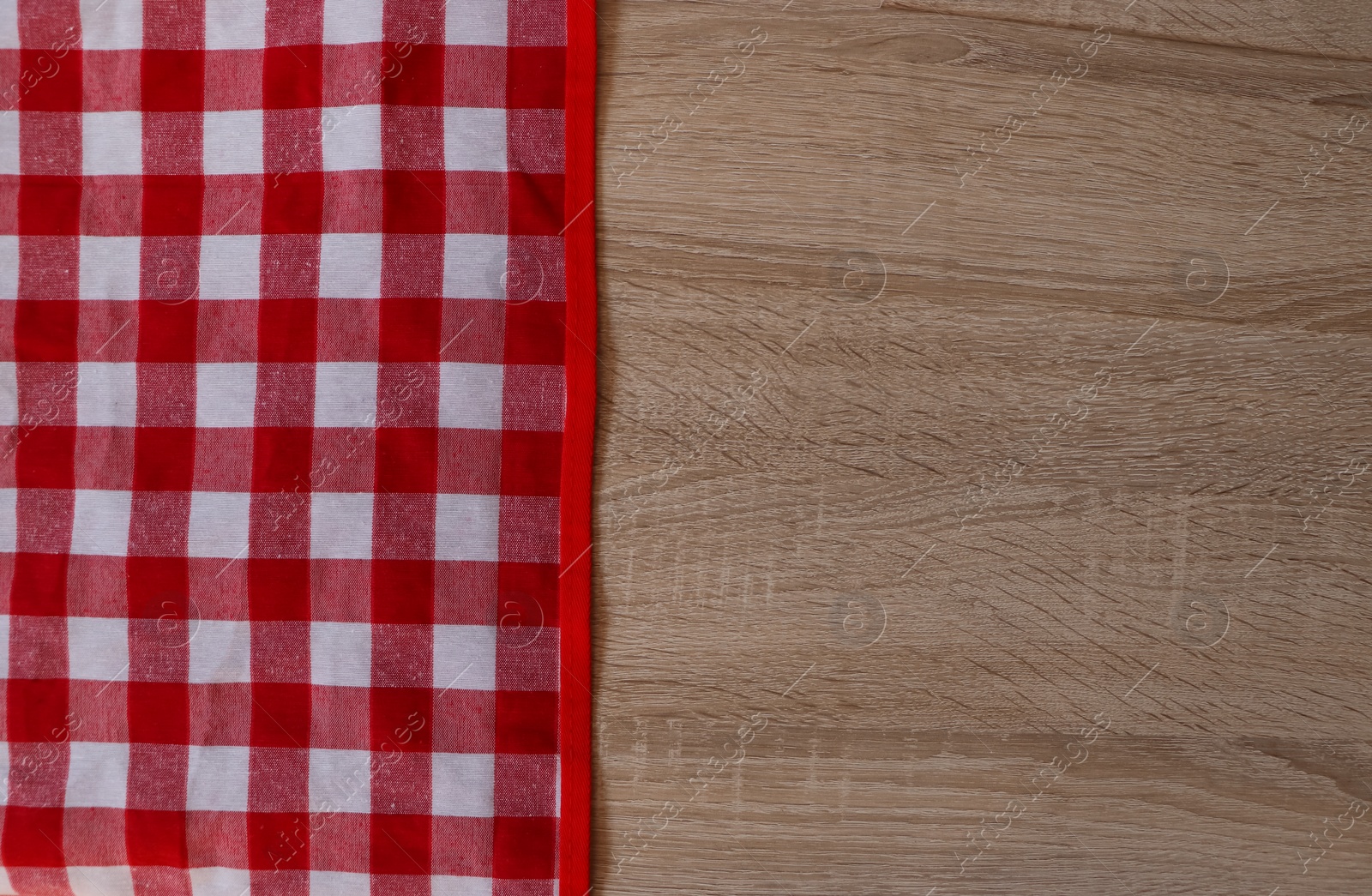 Photo of Checkered picnic cloth on wooden table, top view. Space for text