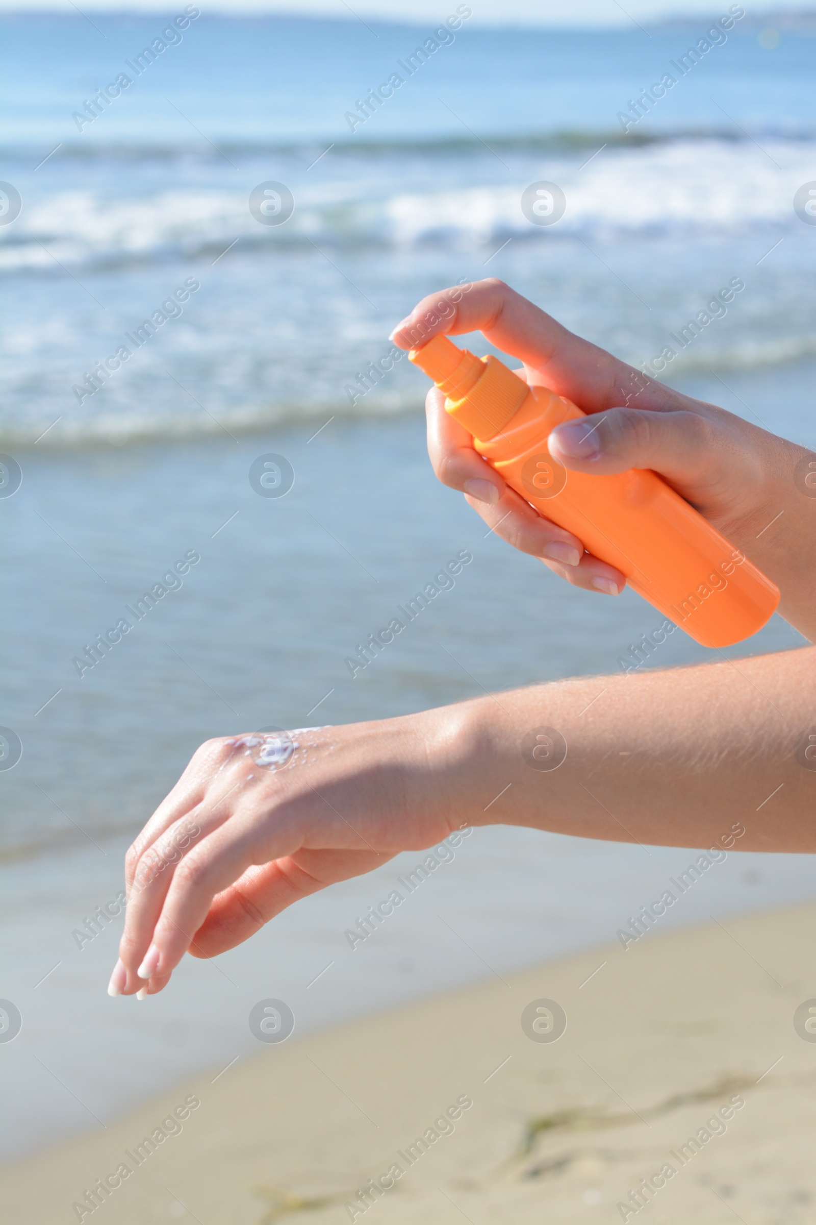 Photo of Woman applying sun protection cream on her hand at beach, closeup