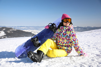 Photo of Young woman with snowboard on hill. Winter vacation