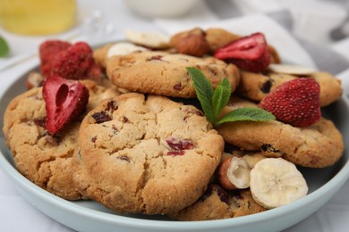 Photo of Cookies with freeze dried fruits, mint and nuts on white table, closeup
