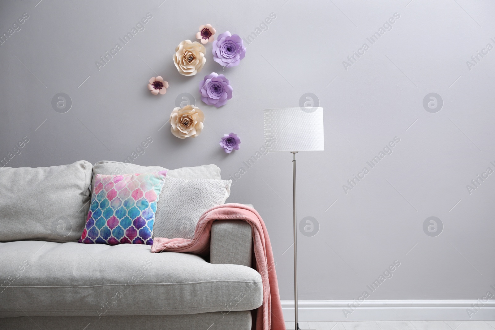 Photo of Comfortable sofa near wall with floral decor in living room