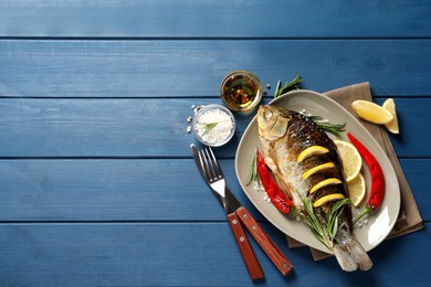 Tasty homemade roasted crucian carp served on blue wooden table, flat lay with space for text. River fish