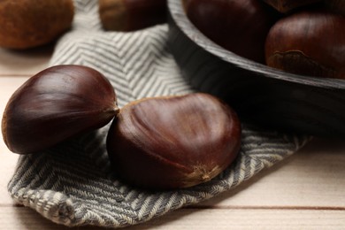 Photo of Sweet fresh edible chestnuts on light wooden table, closeup