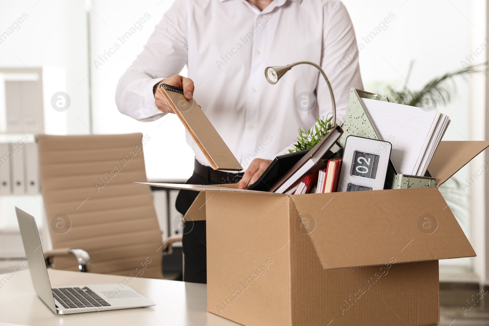 Photo of Young man packing stuff in box at office, closeup