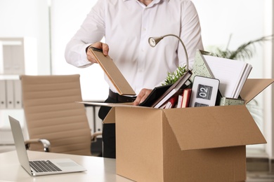 Young man packing stuff in box at office, closeup