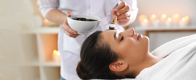 Image of Cosmetologist applying mask onto woman's face in spa salon. Banner design
