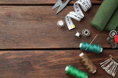 Photo of Threads and other sewing supplies on wooden table, flat lay. Space for text