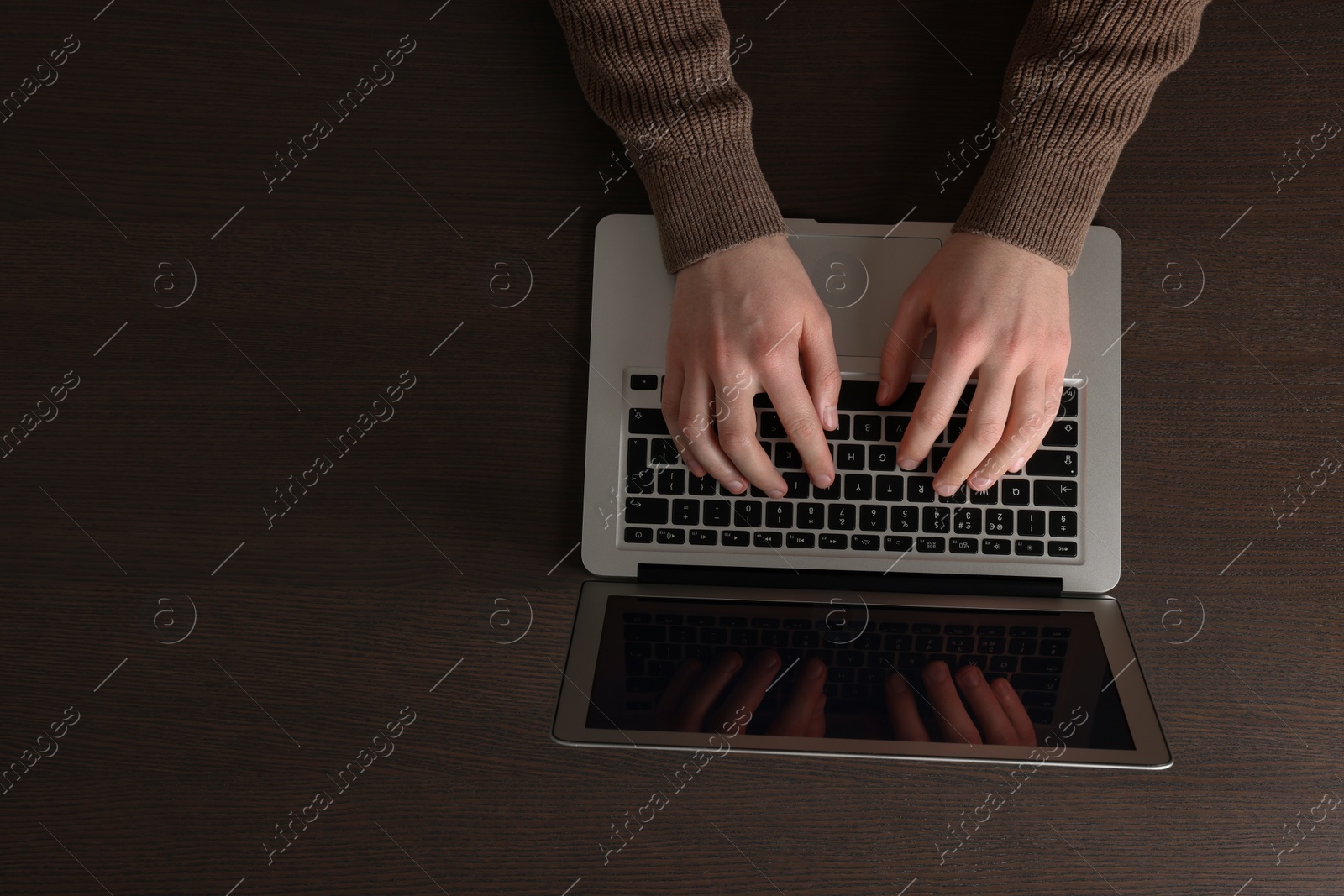 Photo of Man working with laptop at wooden table, top view. Space for text