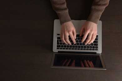 Photo of Man working with laptop at wooden table, top view. Space for text