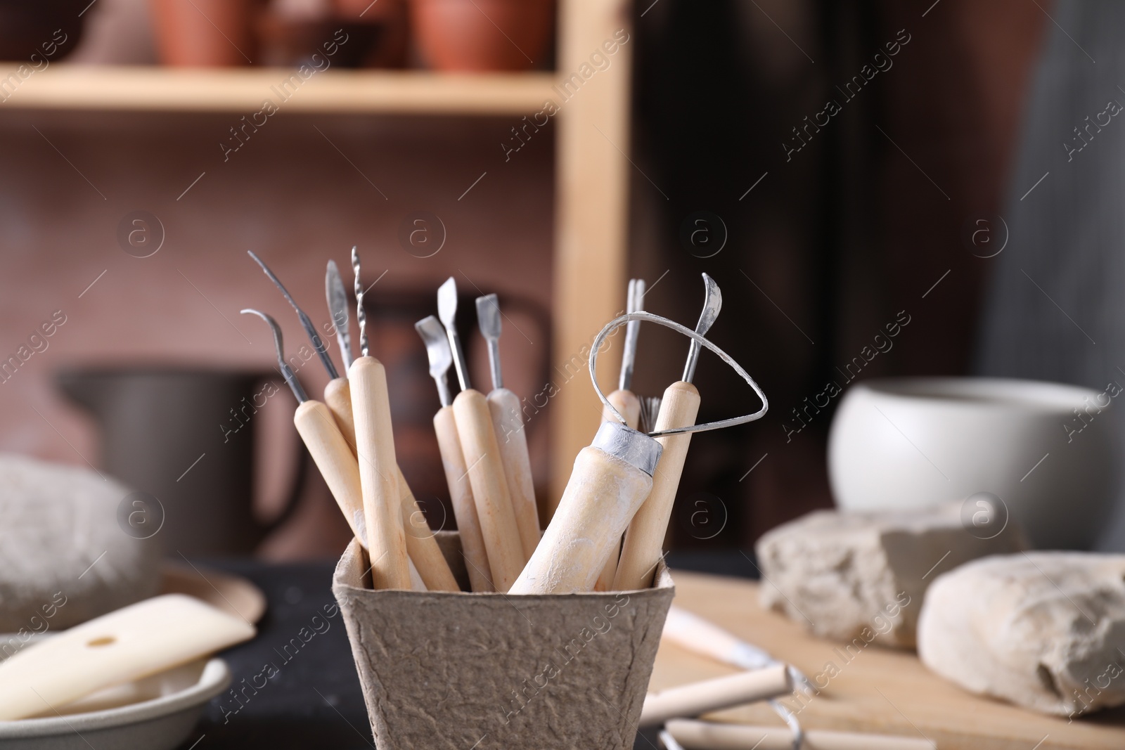 Photo of Clay and set of modeling tools on table in workshop, closeup