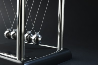 Photo of Newton's cradle on dark background, closeup. Physics law of energy conservation