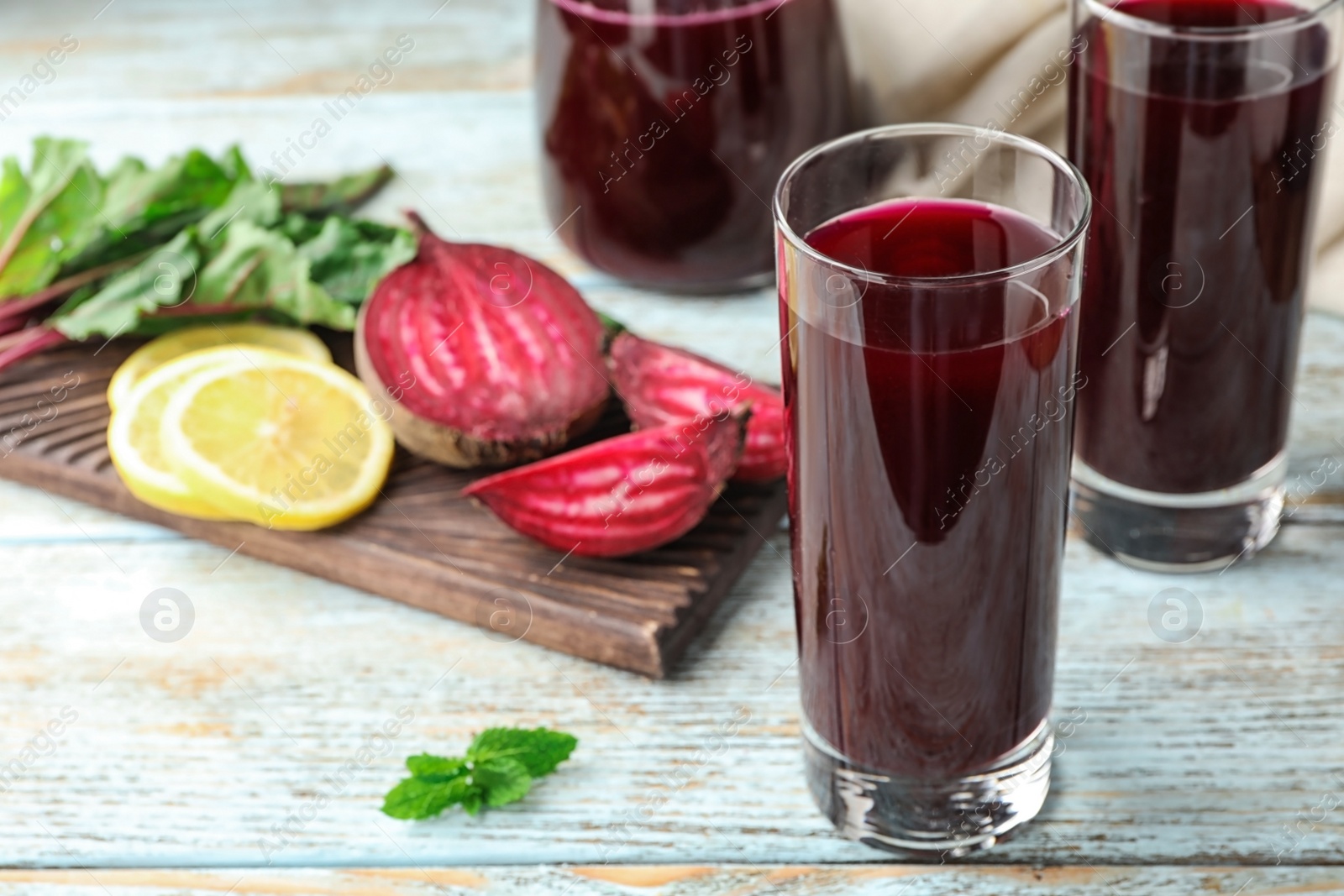 Photo of Glasses of fresh beet juice on blue wooden table. Space for text