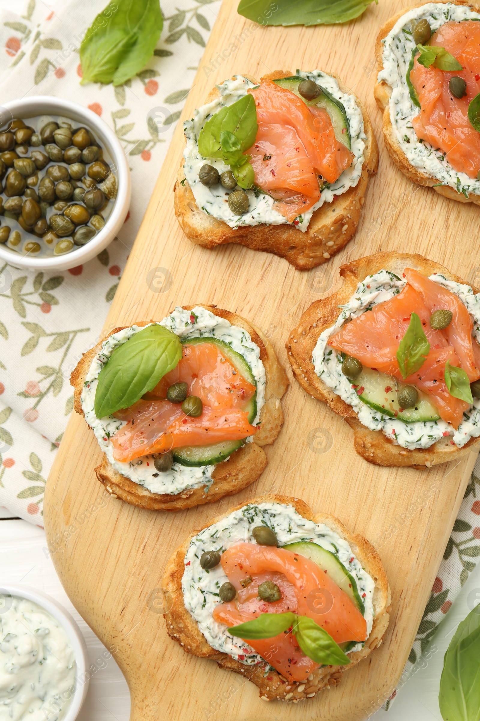 Photo of Tasty canapes with salmon, capers, cucumber and sauce on table, top view