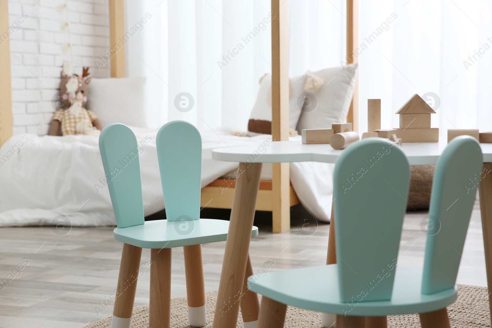 Photo of Little table and chairs with bunny ears in children's room. Interior design