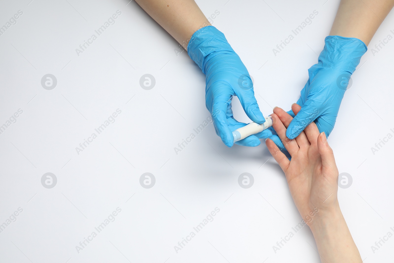 Photo of Diabetes. glucose testing. Doctor using lancet pen on white background, top view