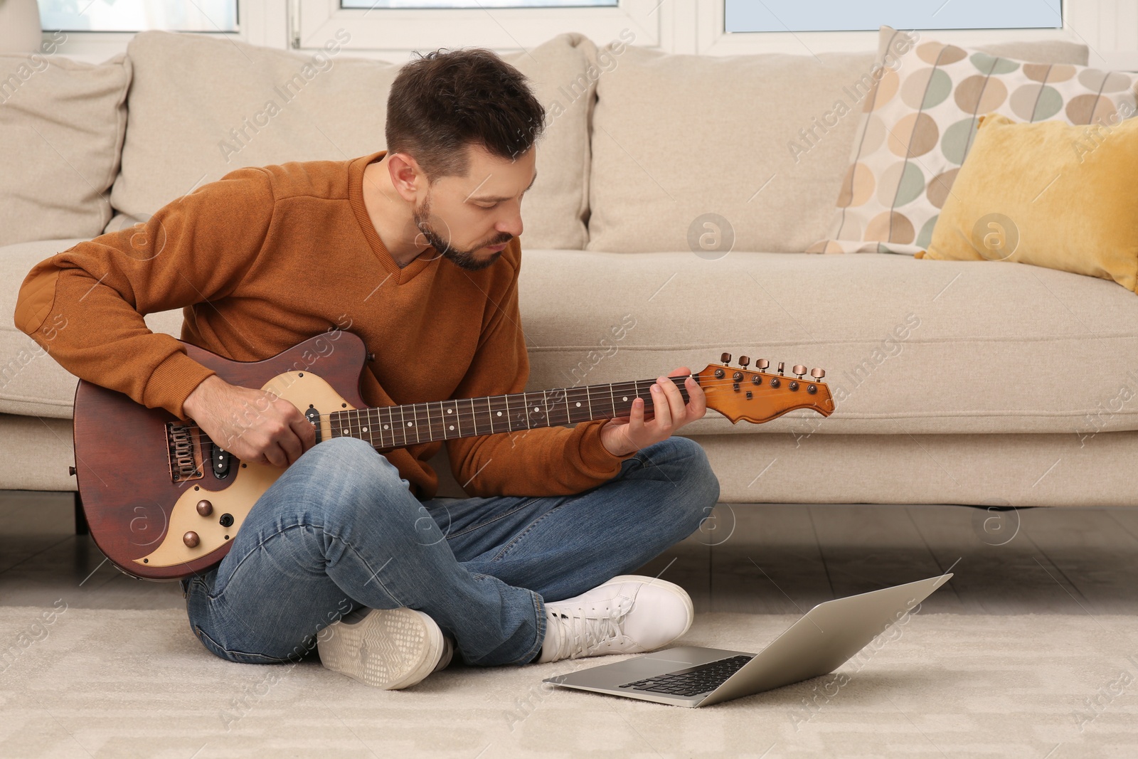 Photo of Man learning to play guitar with online music course at home. Time for hobby