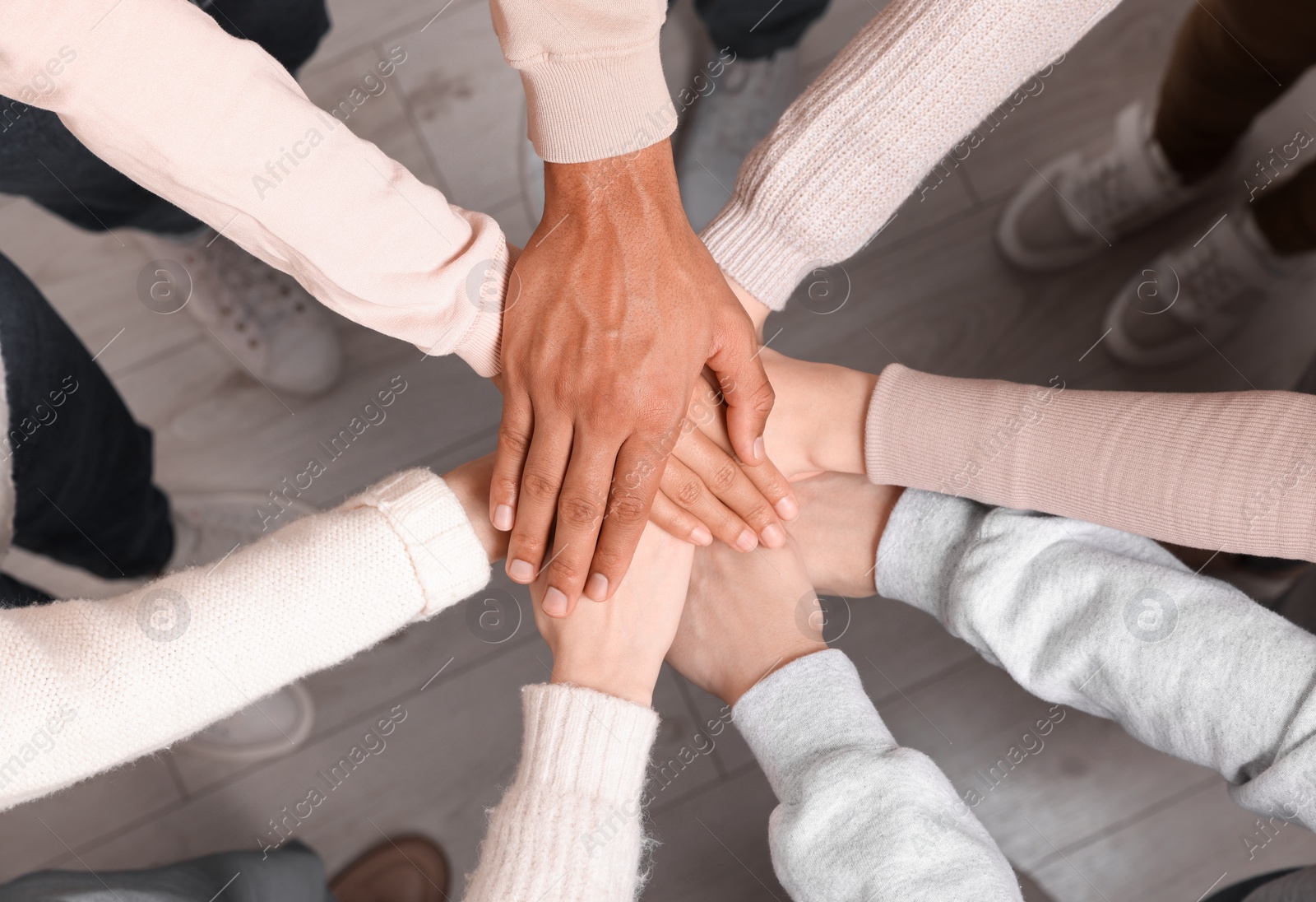 Photo of Group of multiracial people joining hands together indoors, top view