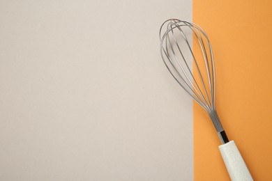 Photo of Metal whisk on color background, top view. Space for text