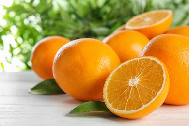 Fresh juicy oranges with leaves on wooden table