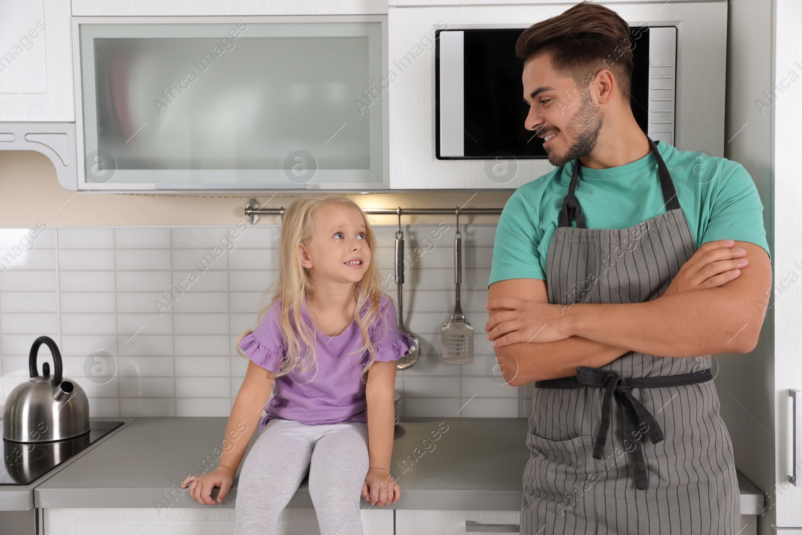 Photo of Young man and his daughter near microwave oven in kitchen