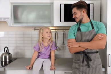 Young man and his daughter near microwave oven in kitchen