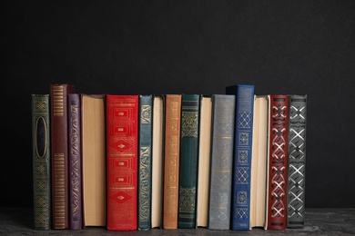 Stack of hardcover books on grey stone table against black background