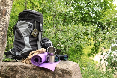 Backpack and camping equipment on stone in forest. Space for text