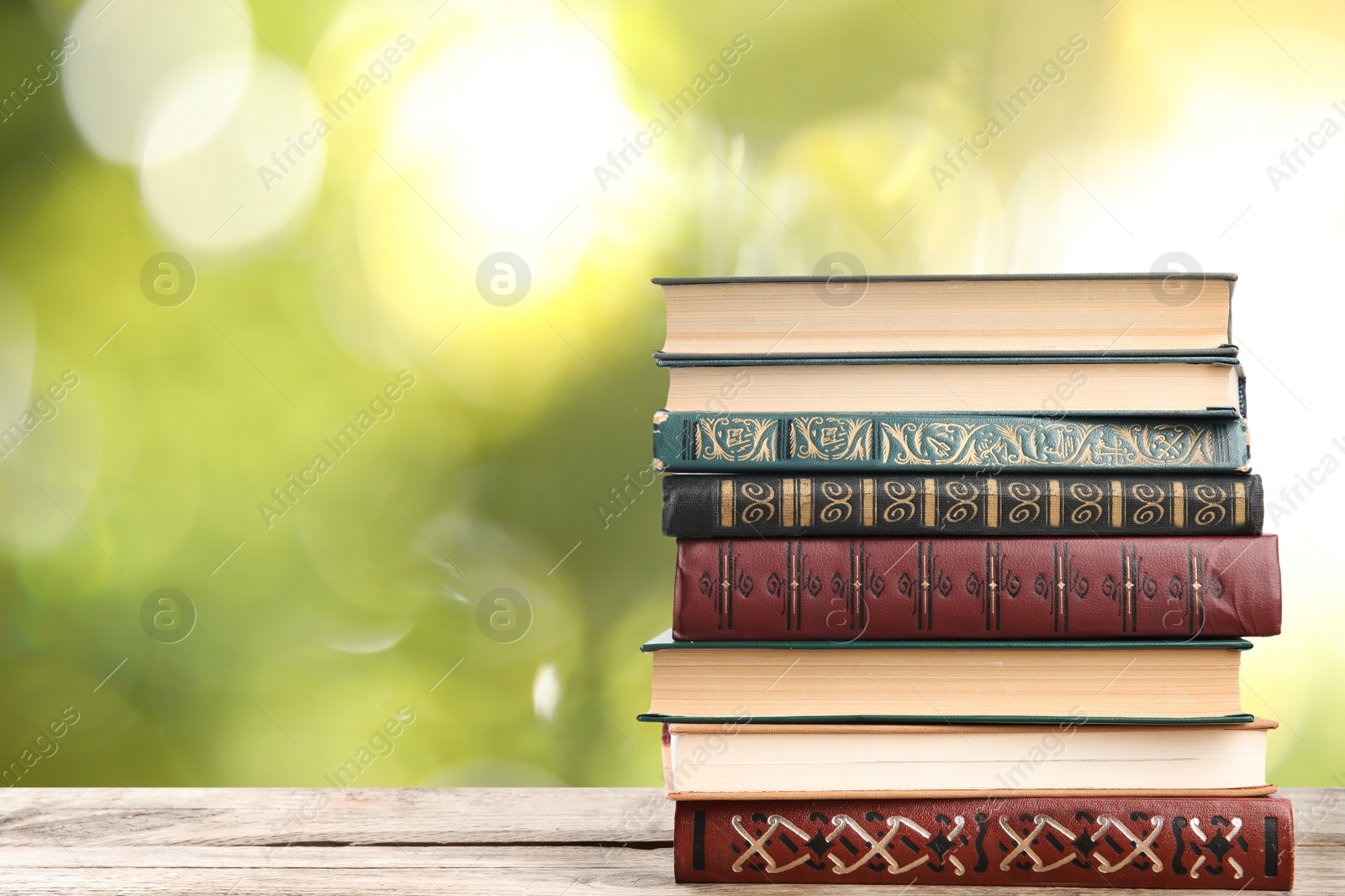 Image of Collection of different books on wooden table against blurred green background, space for text