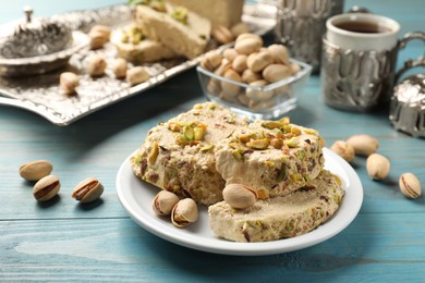 Photo of Tasty halva with pistachios served on light blue wooden table