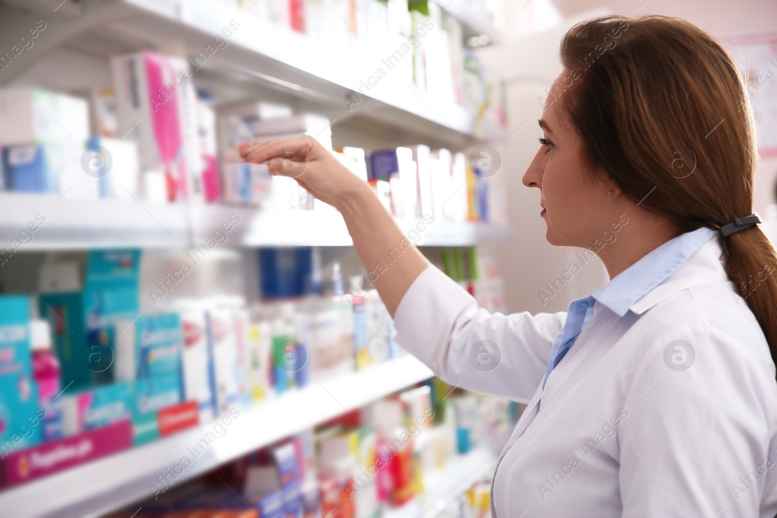 Photo of Professional pharmacist near shelves with merchandise in drugstore