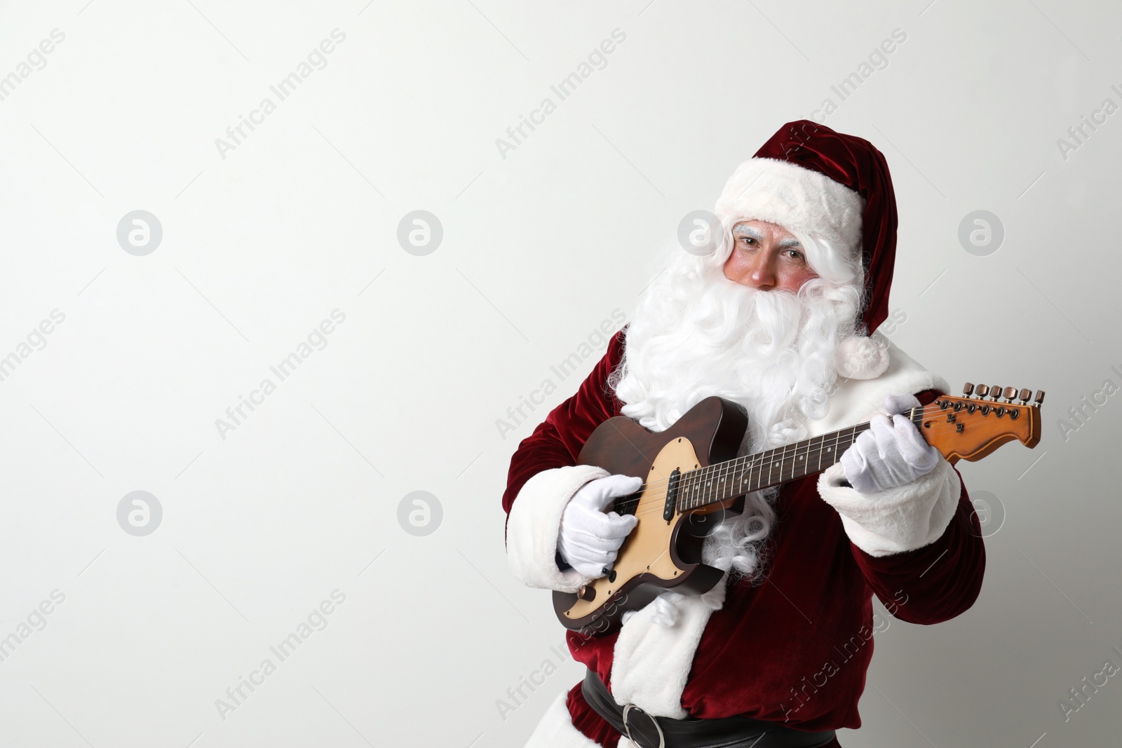 Photo of Santa Claus playing electric guitar on light background, space for text. Christmas music