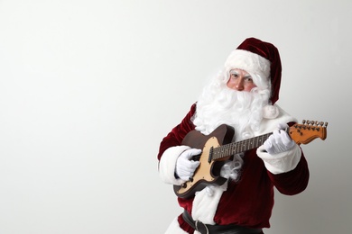 Photo of Santa Claus playing electric guitar on light background, space for text. Christmas music