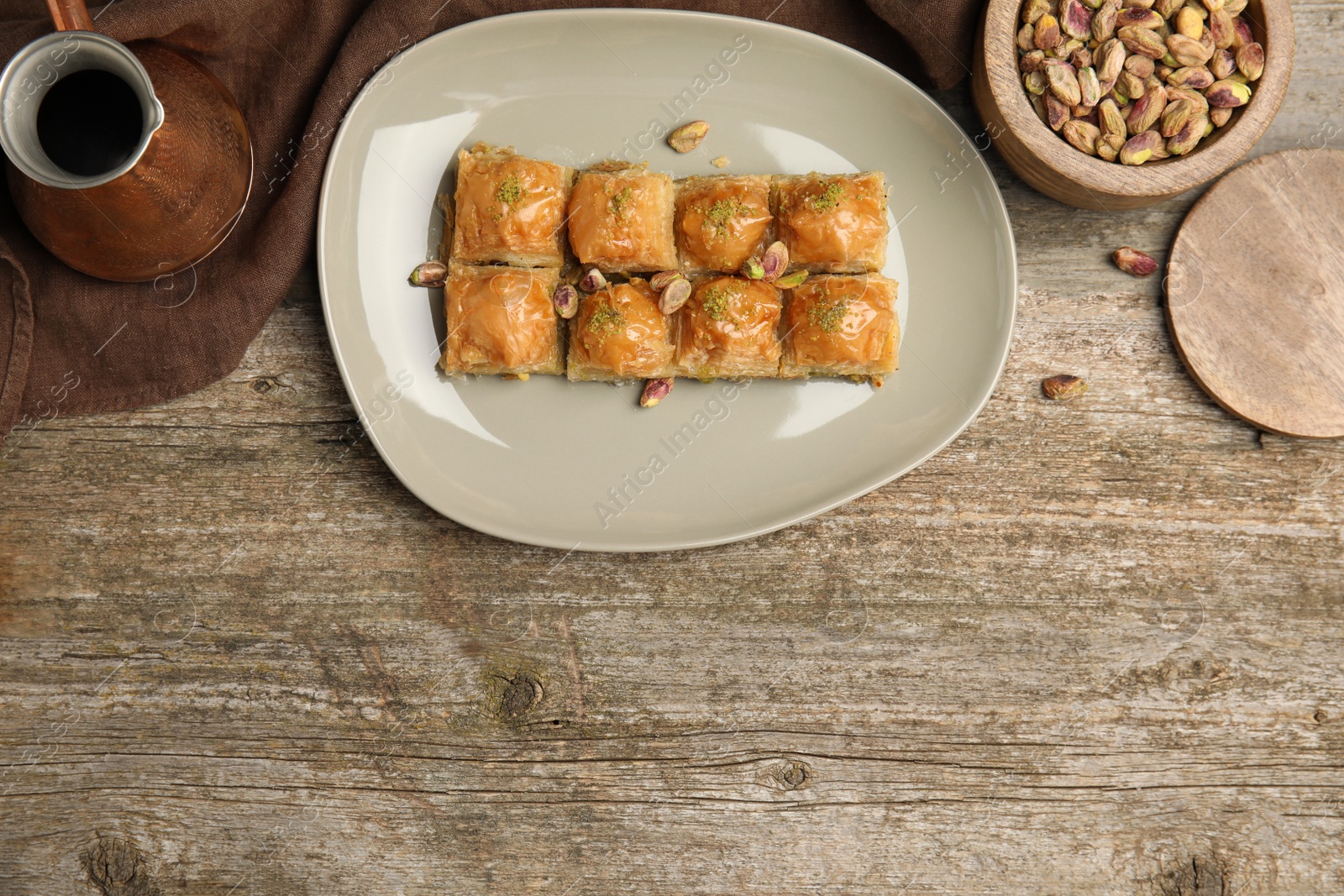 Photo of Delicious baklava with pistachios and hot coffee on wooden table, flat lay. Space for text