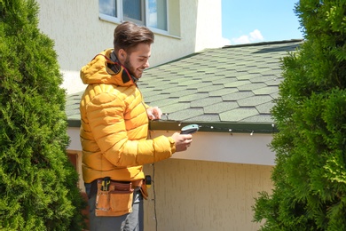 Young man decorating roof with Christmas lights