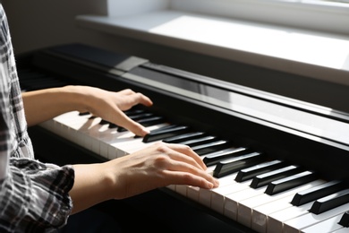 Photo of Young woman playing piano at home, closeup