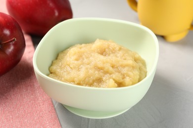 Photo of Healthy baby food. Bowl with delicious apple puree on light grey table, closeup