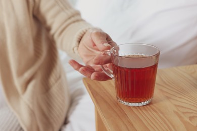 Elderly woman with cup of hot tea indoors, closeup. Home care service