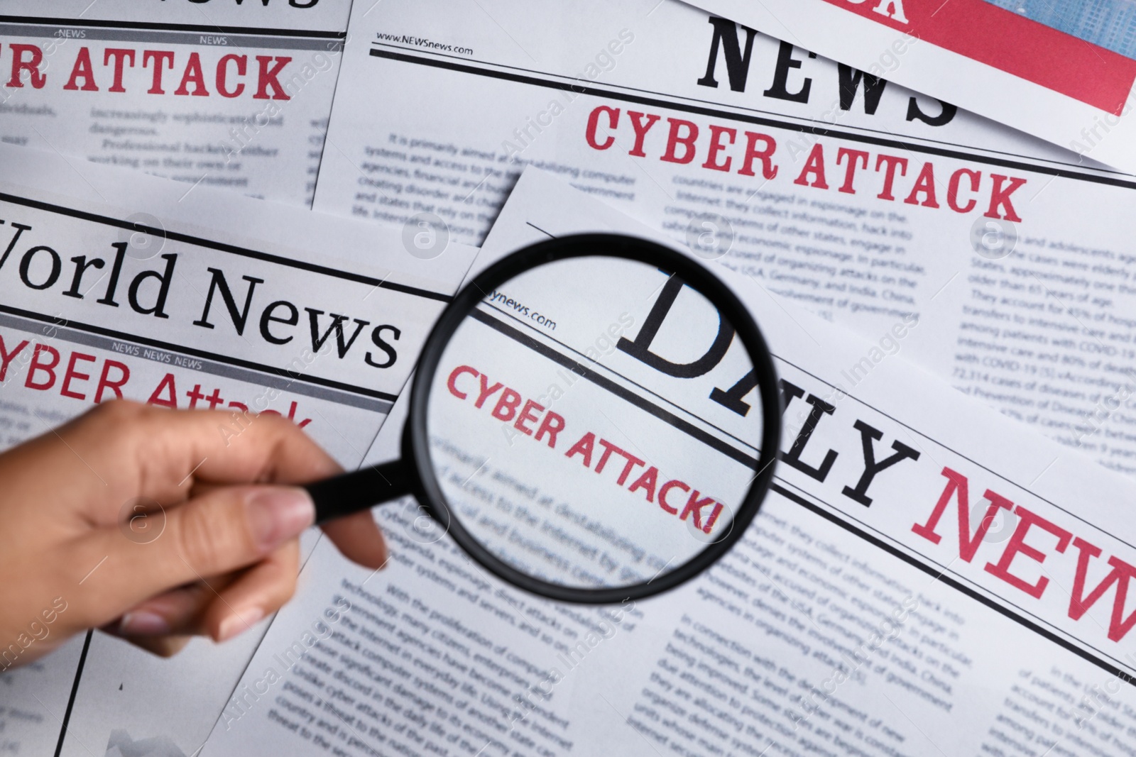 Photo of Woman using magnifying glass to read newspaper with headline CYBER ATTACK, top view