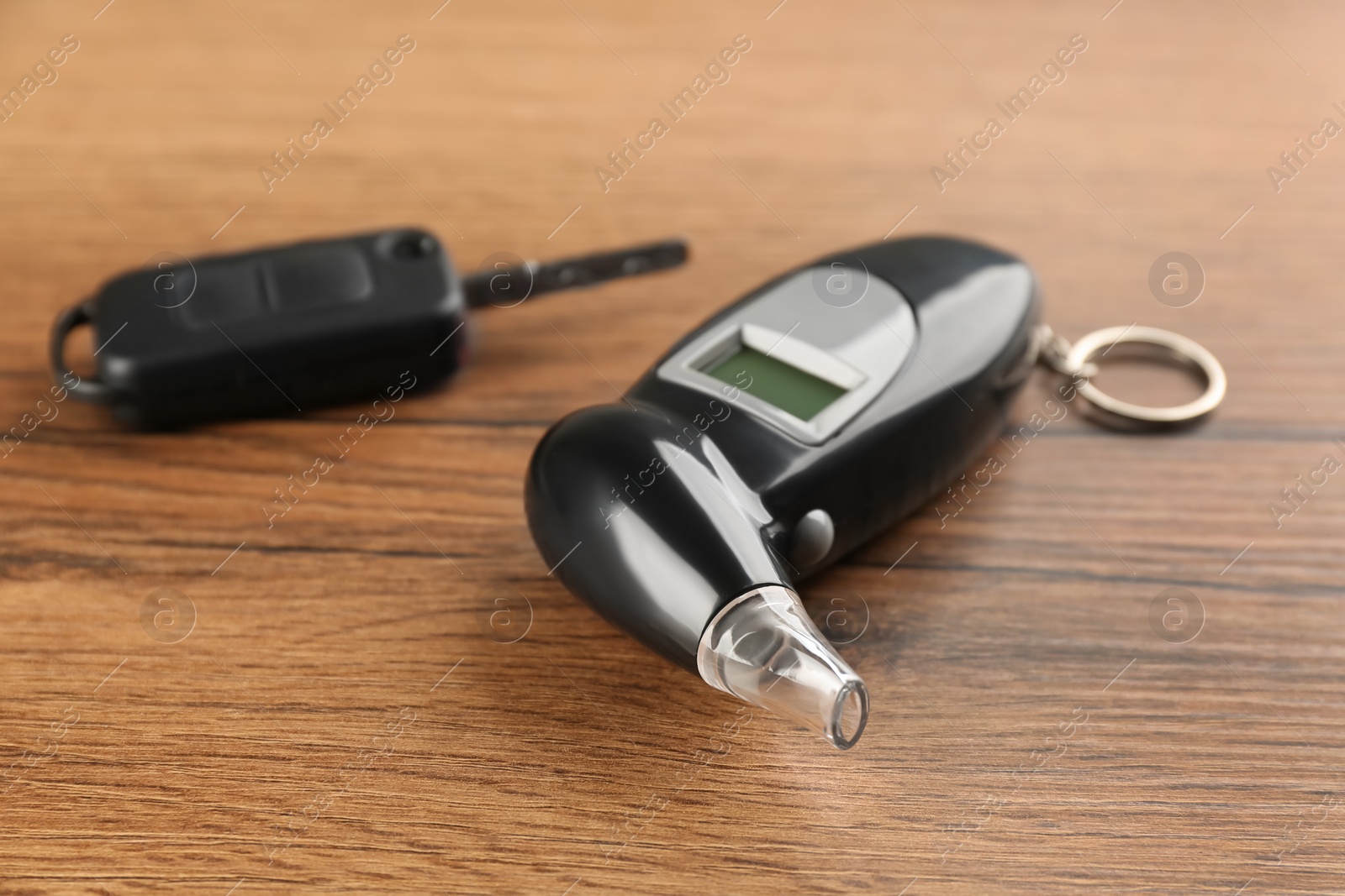 Photo of Modern breathalyzer and car key on wooden table