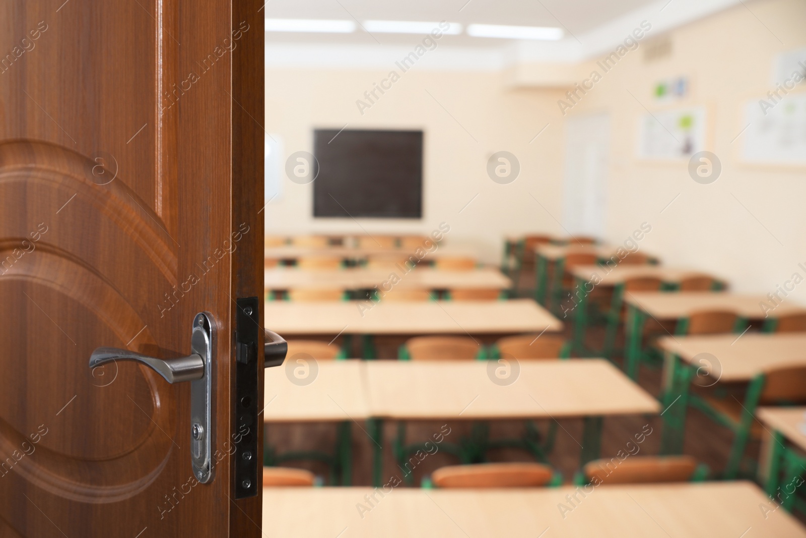 Image of Wooden door open into modern empty classroom