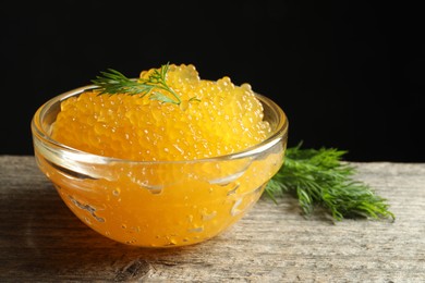 Photo of Fresh pike caviar in bowl on wooden table, closeup