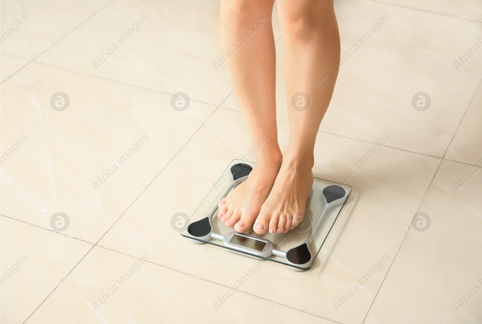 Photo of Woman standing on scales indoors. Overweight problem