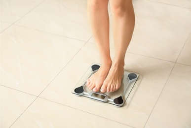 Photo of Woman standing on scales indoors. Overweight problem