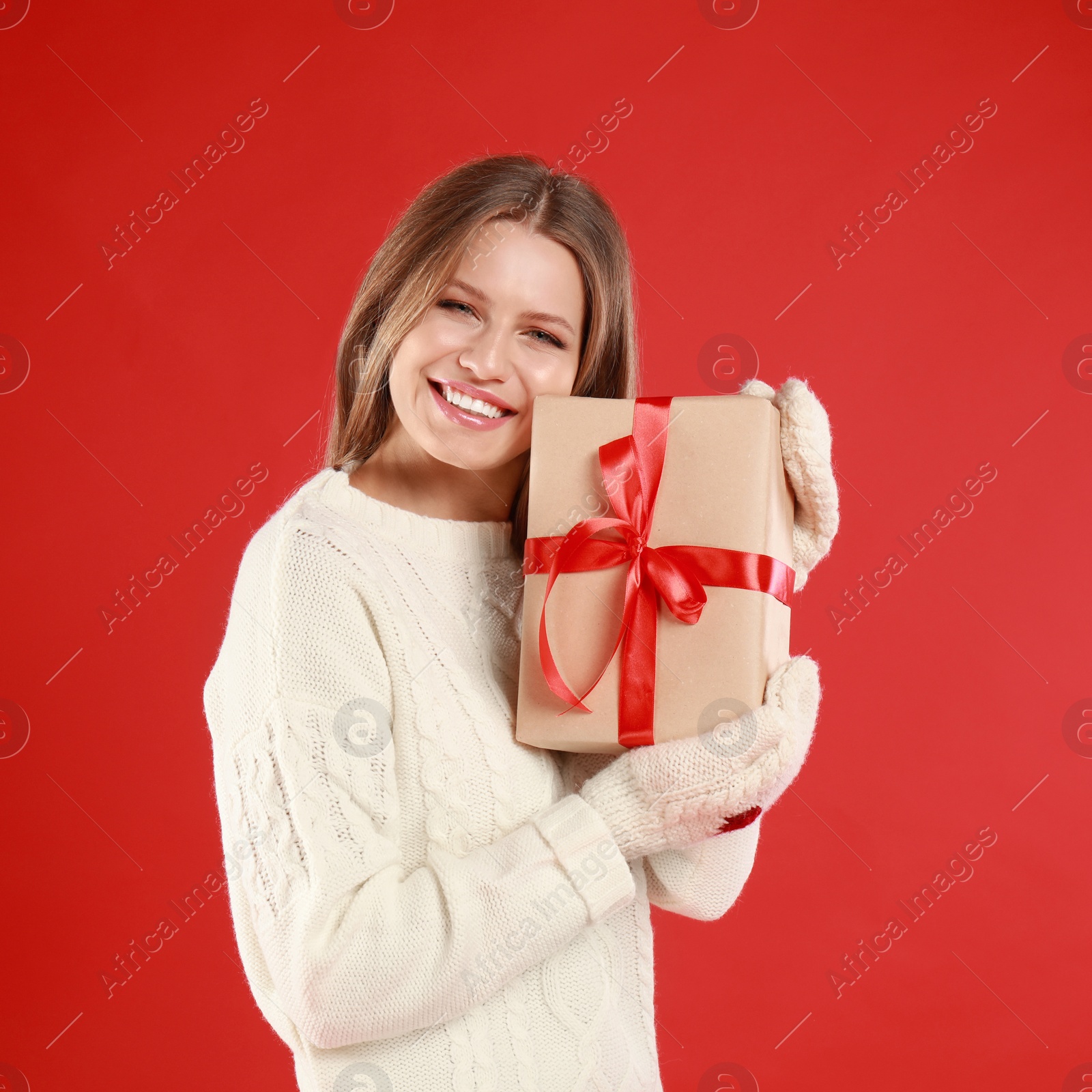 Photo of Happy young woman with Christmas gift on red background